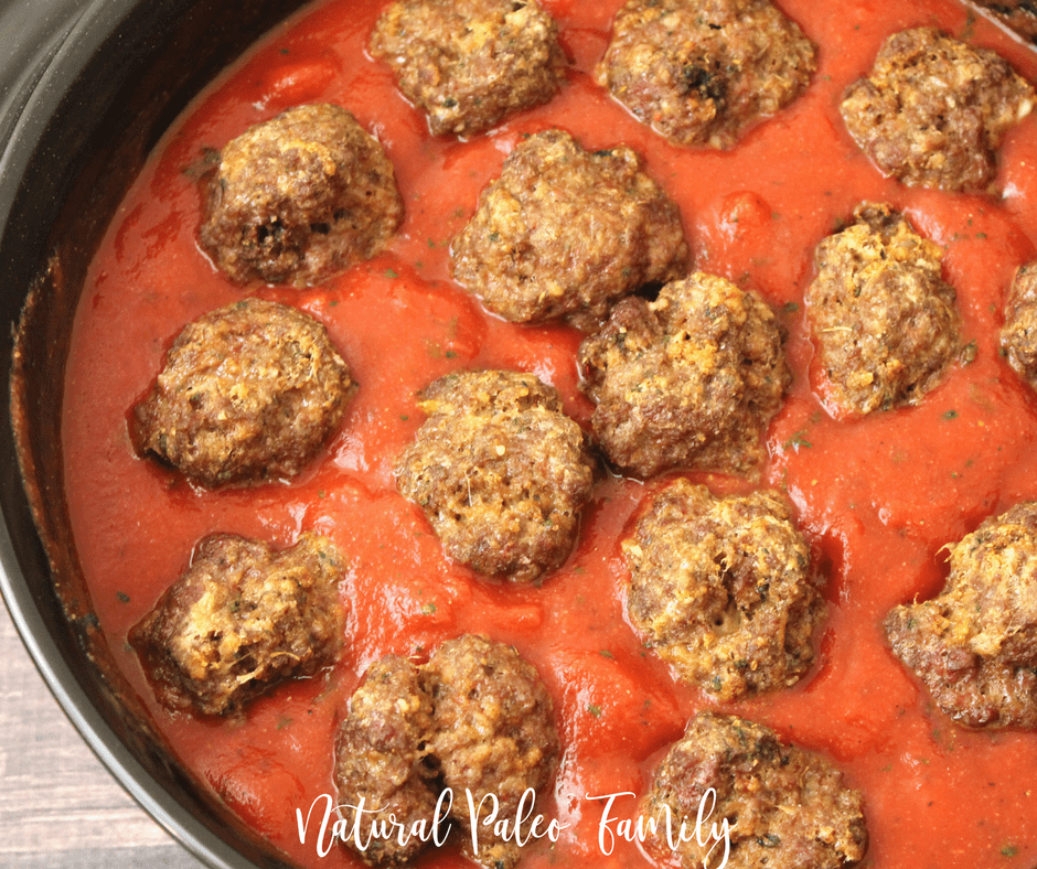 paleo meatballs placed on top of spaghetti sauce in a sauce pan