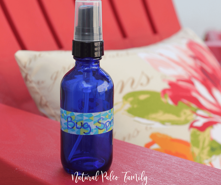 homemade bug spray in a blue spray bottle on the arm of a red Adirondack chair