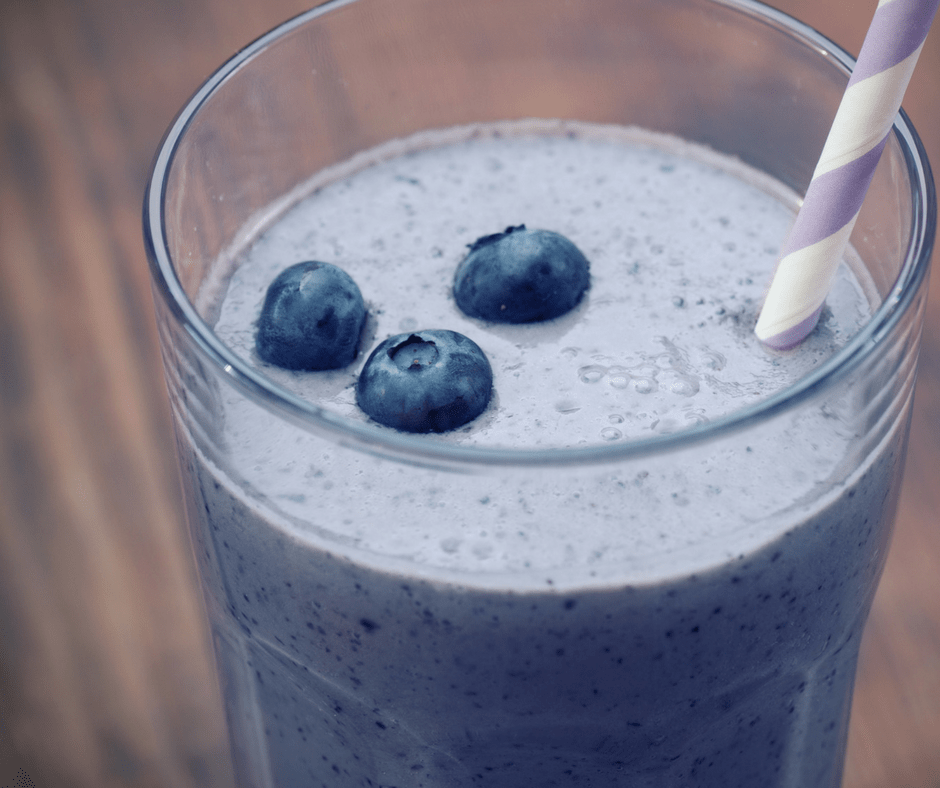 blueberry smoothie in a glass with a straw