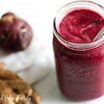 Beet smoothie in a jar next to a beet and ginger
