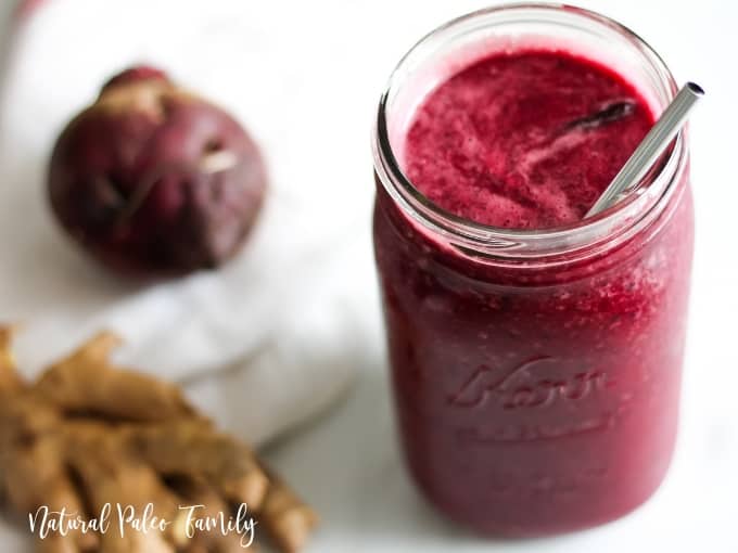 Beet smoothie in a jar next to a beet and ginger