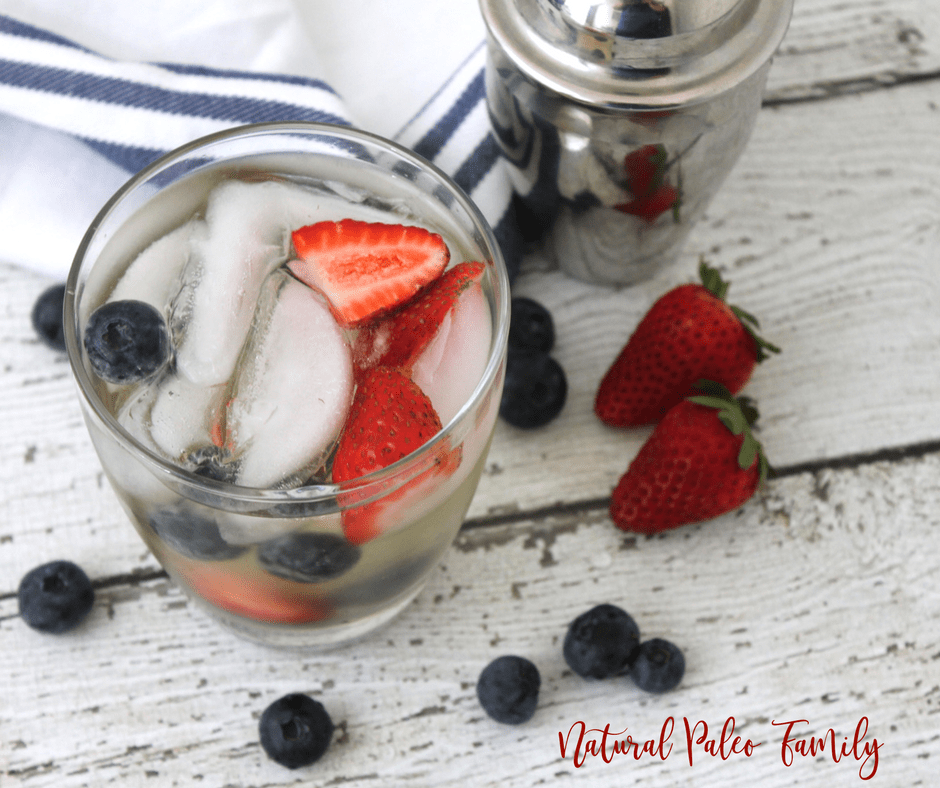 patriotic paleo margarita with silver shaker cup, strawberries, and blueberries