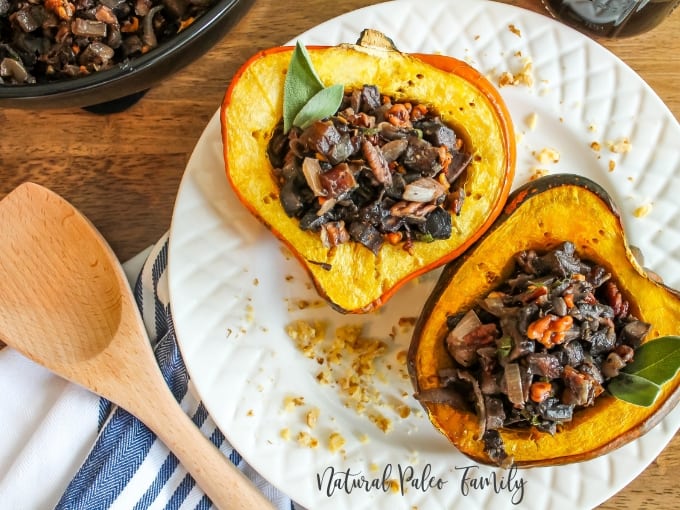 two mushroom stuffed acorn squash on a white plate