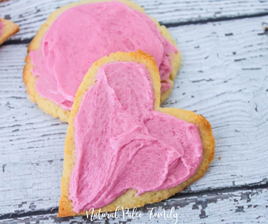 two pink frosted paleo valentine's day cookies on white wood